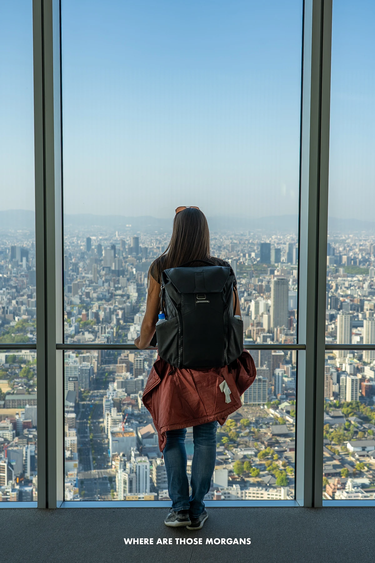 Kristen from Where Are Those Morgans standing against a ceiling to floor window looking at views over Osaka