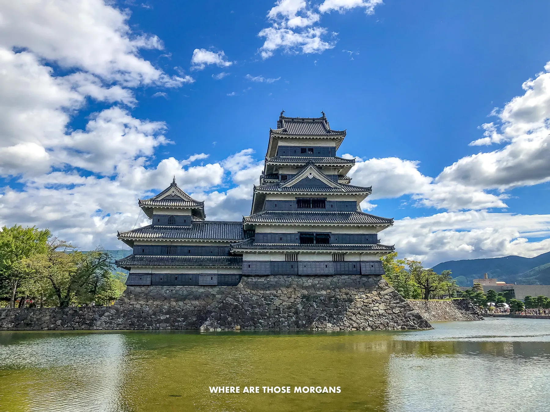 The original Matsumoto Castle behind a wide moat on a sunny day with blue sky and light clouds in Japan