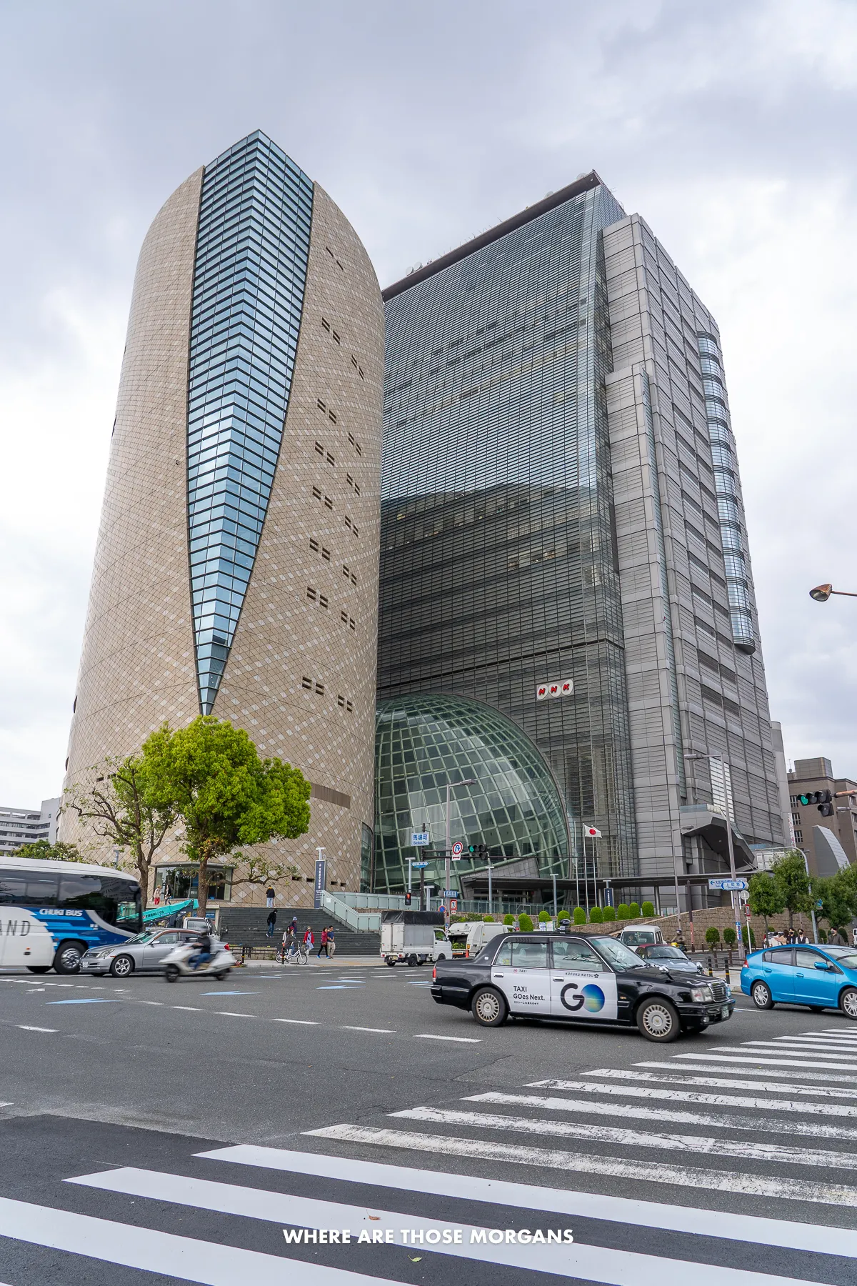 Looking at the Osaka Museum of History building from outside on a pedestrian crossing over a road with cars