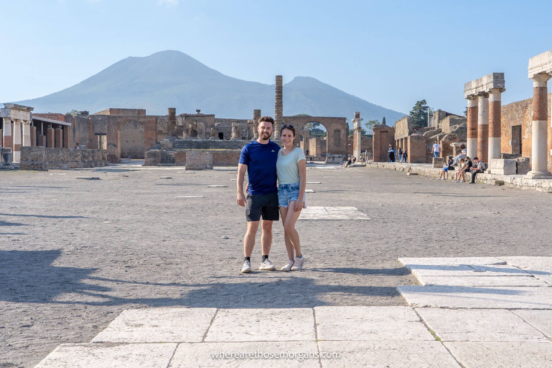 Photo of Mark and Kristen Morgan standing together among the ruins of Pompeii on a clear sunny day