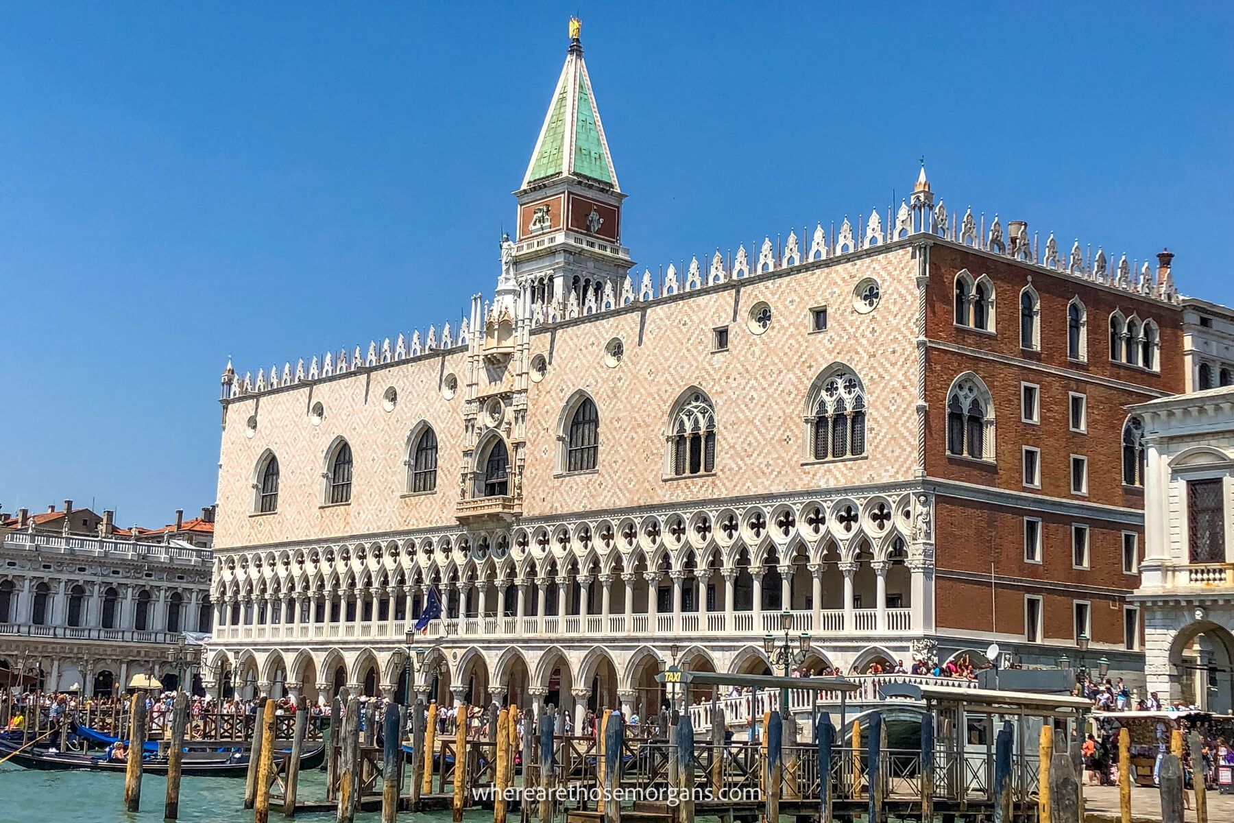 Photo of the outside of the Doge's Palace in Venice taken from a canal on a sunny day with clear blue sky