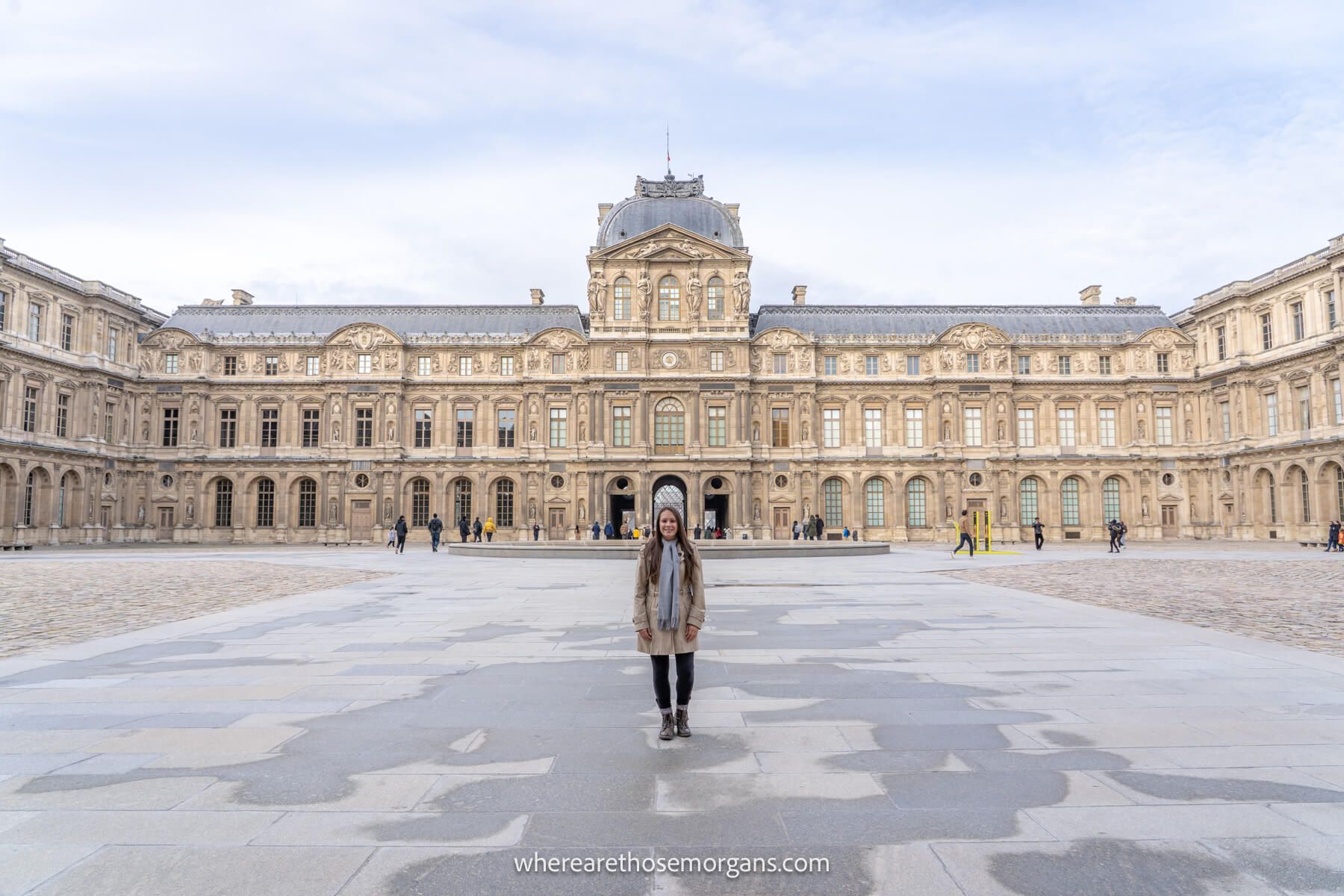 Photo of Kristen Morgan standing in a courtyard in front of the Louvre Museum