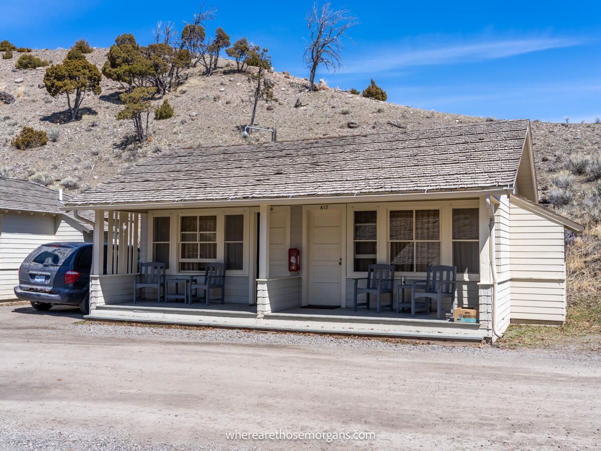 Semi detached wooden cabin on a dirt road with an arid hill behind on a clear day