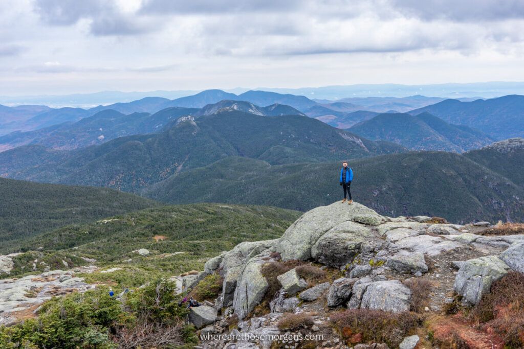 Hiker standing on a rock at the summit of Mount Marcy hike in the Adirondacks near Lake Placid