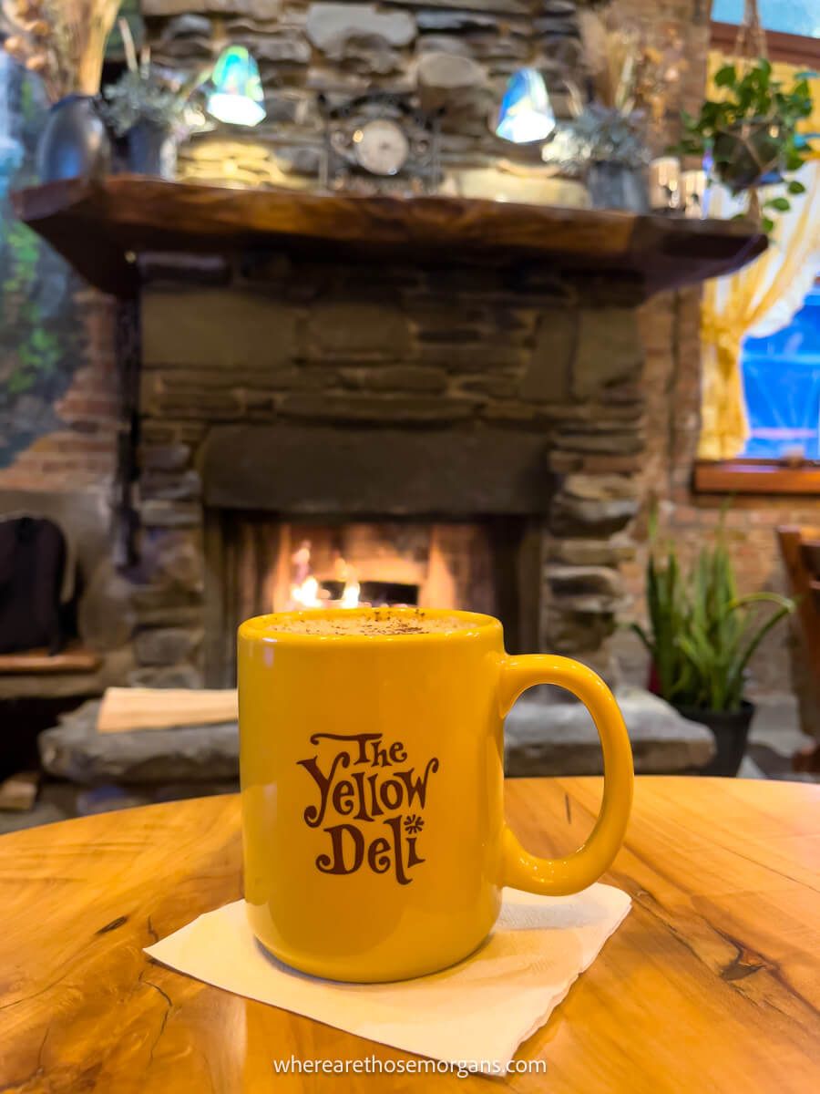 Yellow mug from the Yellow Deli sitting on a  table in front of a fireplace