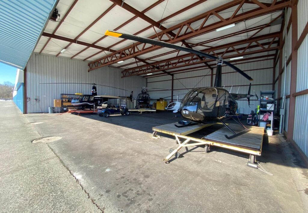 Two choppers sitting in a garage for Wings Air Helicopters company