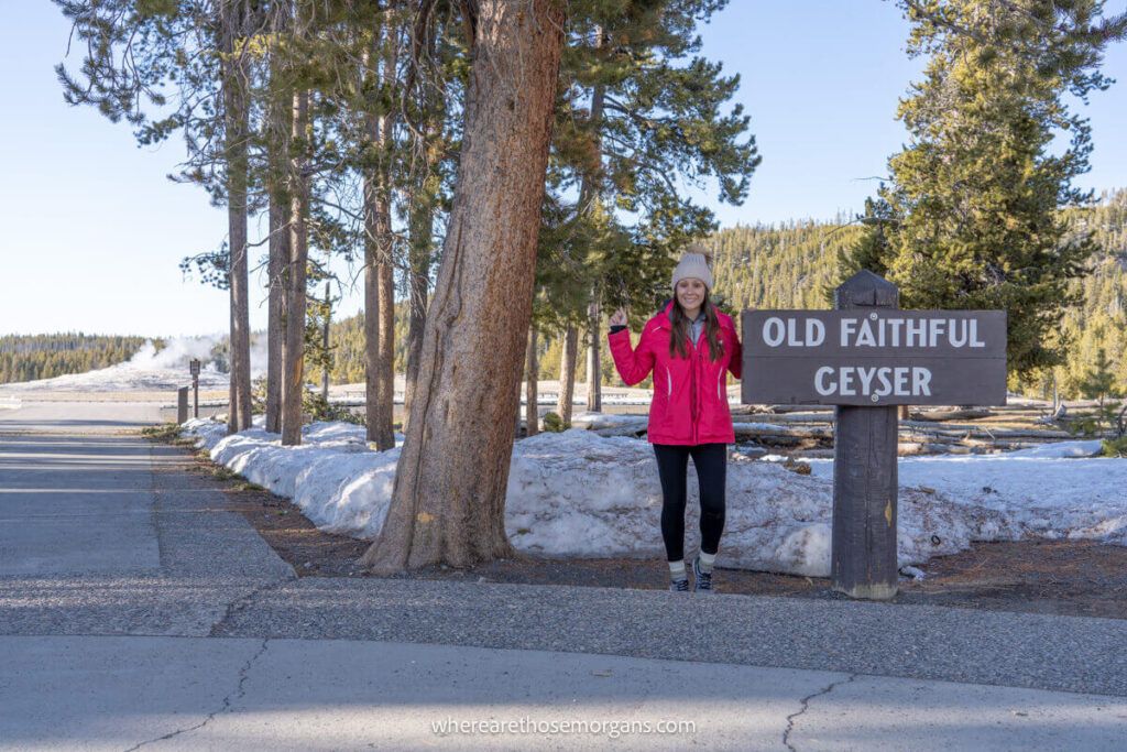 Woman standing next to the Old Faithful sign