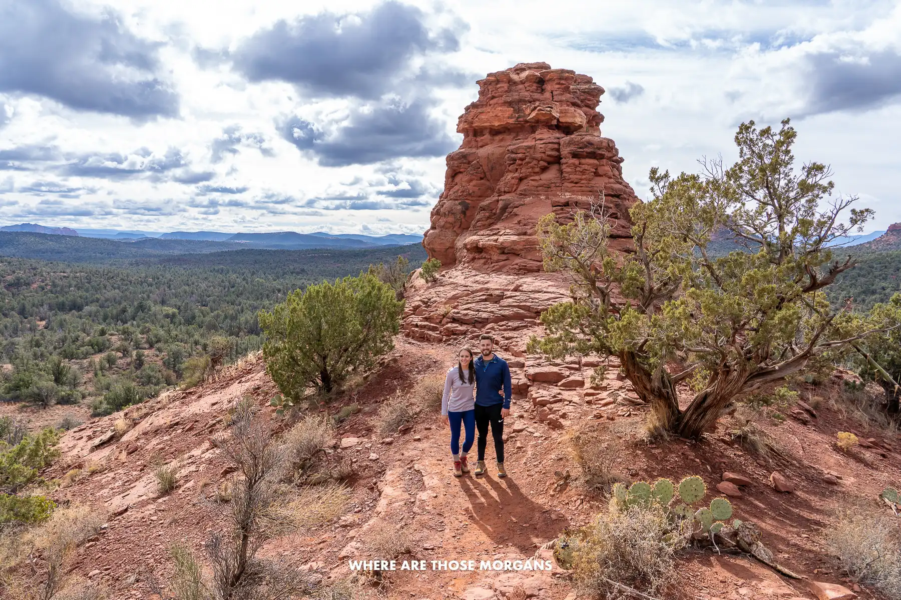 Mark and Kristen from Where Are Those Morgans standing alone together for a photo on red rocks with distant views in Boynton Canyon vortex site