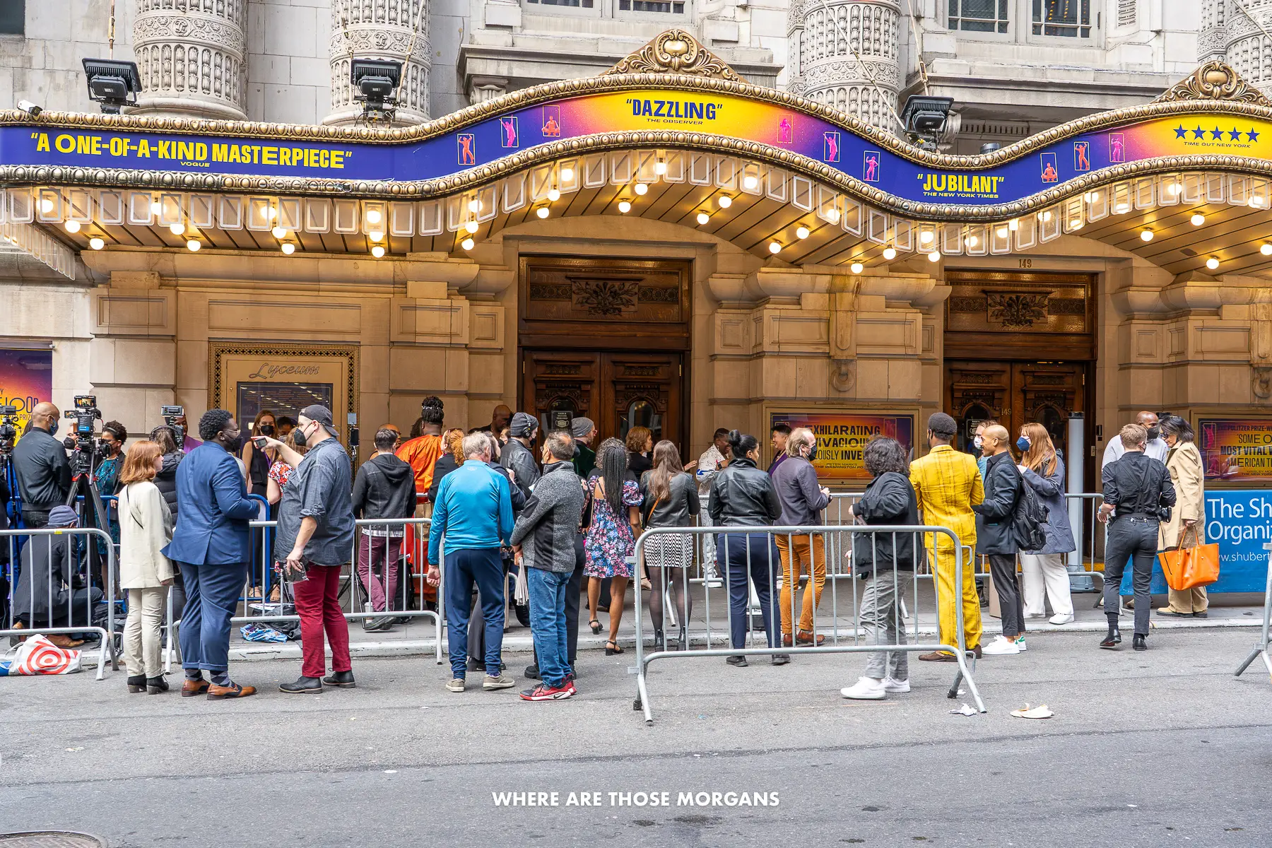 People crowding outside a broadway theater in New York with cameras and railings waiting for the cast to arrive
