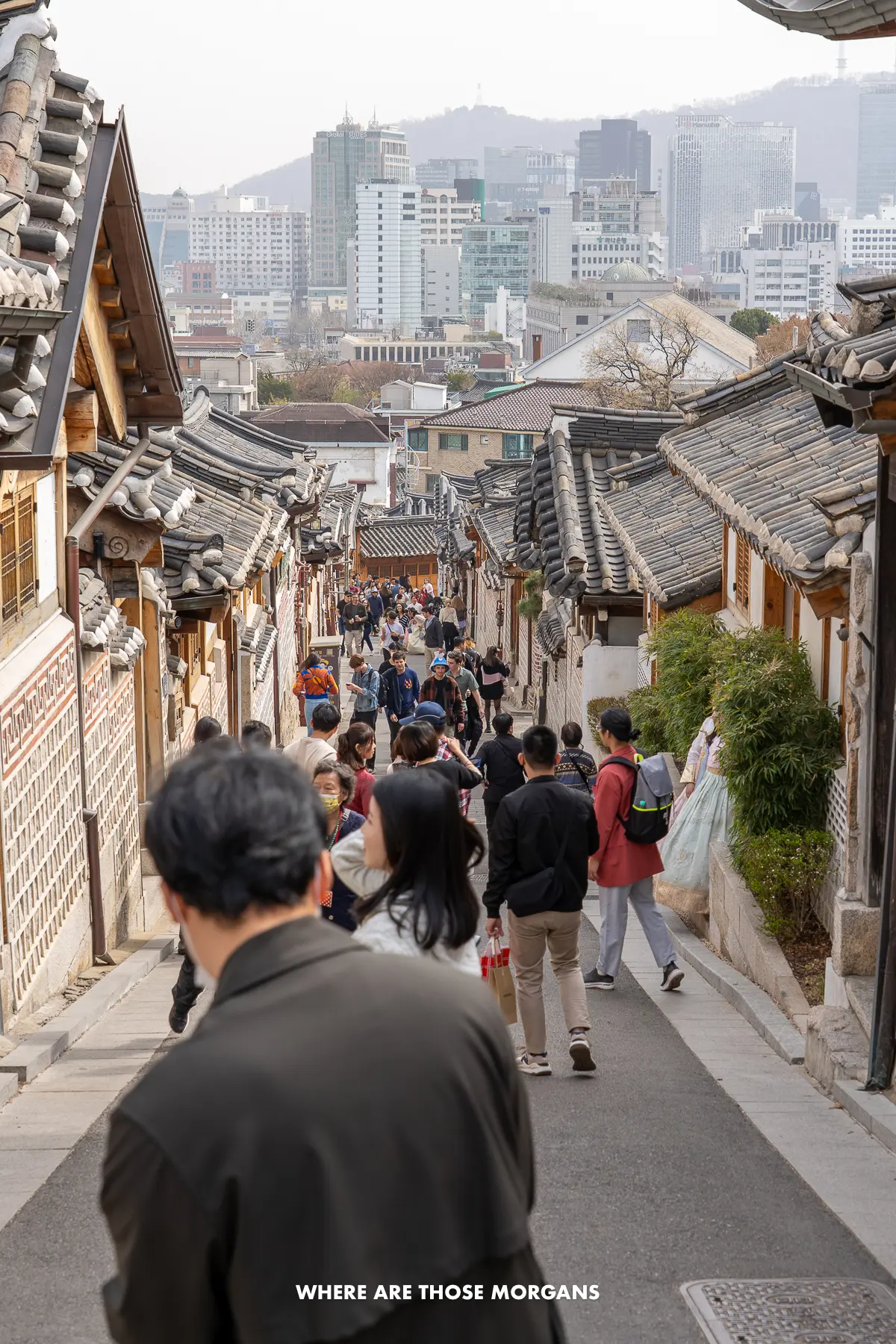 Lots of tourists taking photos on a narrow street in Bukchon Hanok Village in Seoul