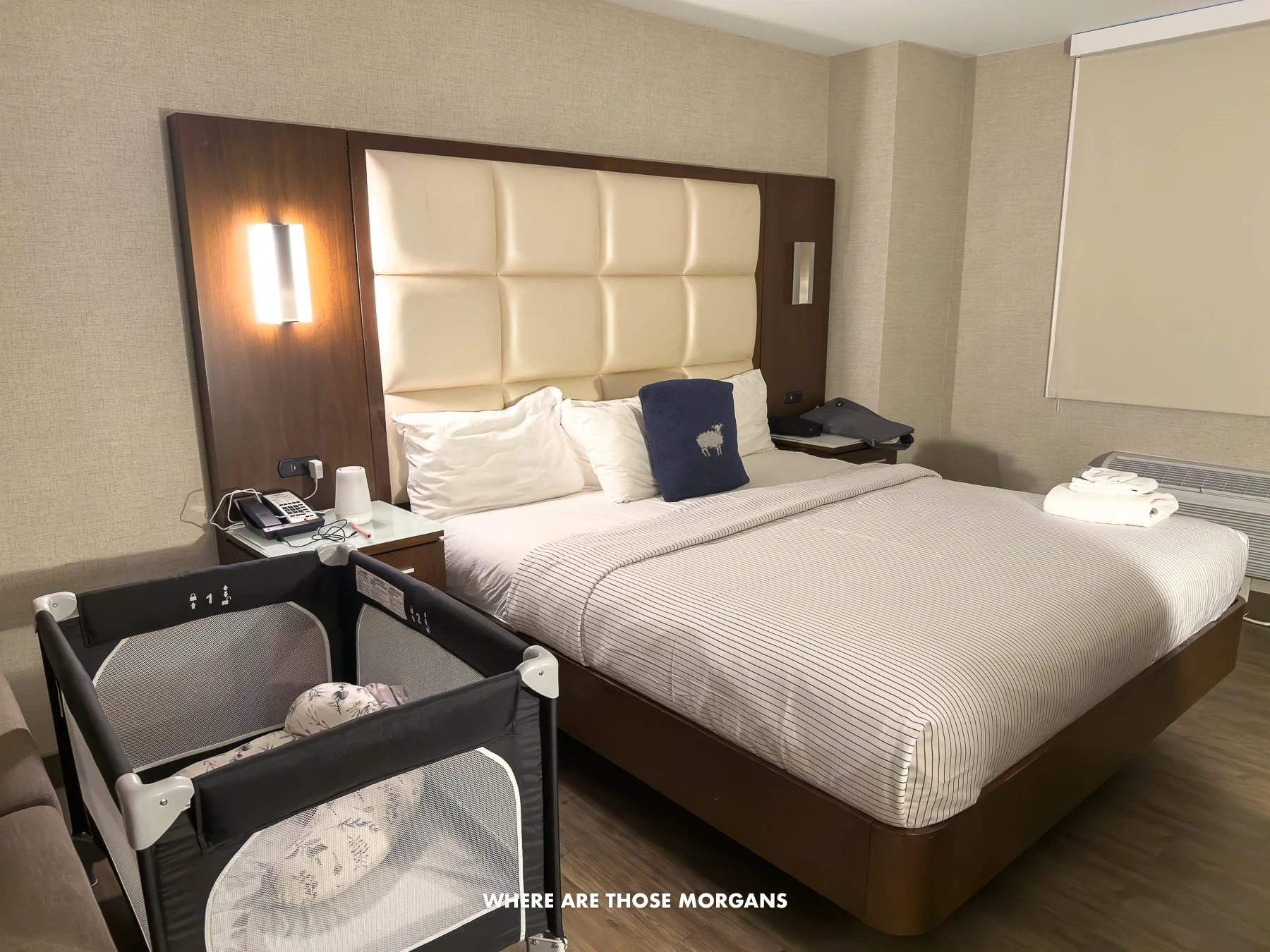 Inside a guest room at the Cambria Hotel in NYC with a bed and crib set up