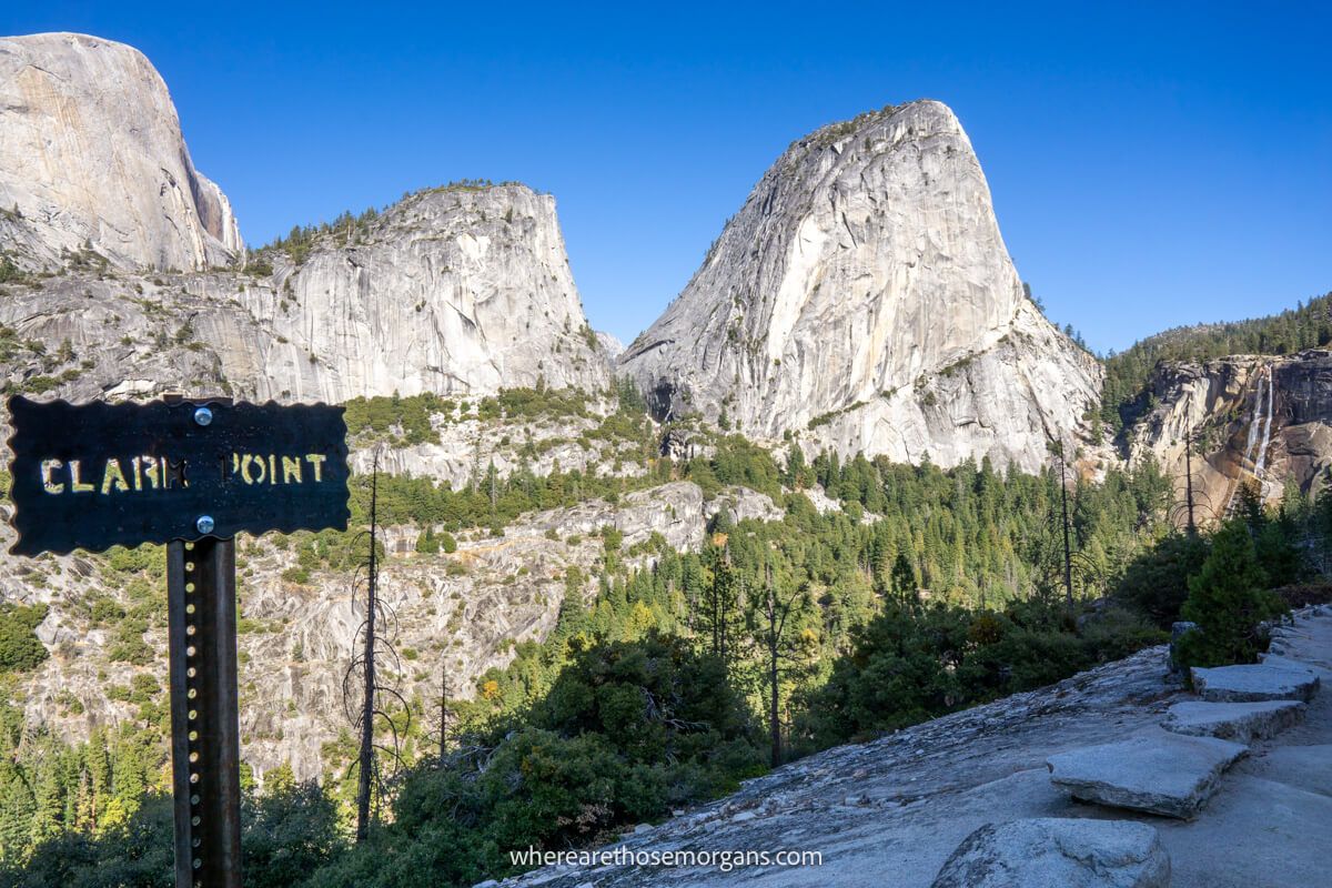Hiking trail with a sign saying Clark Point and views over towering granite monoliths on a clear day in California