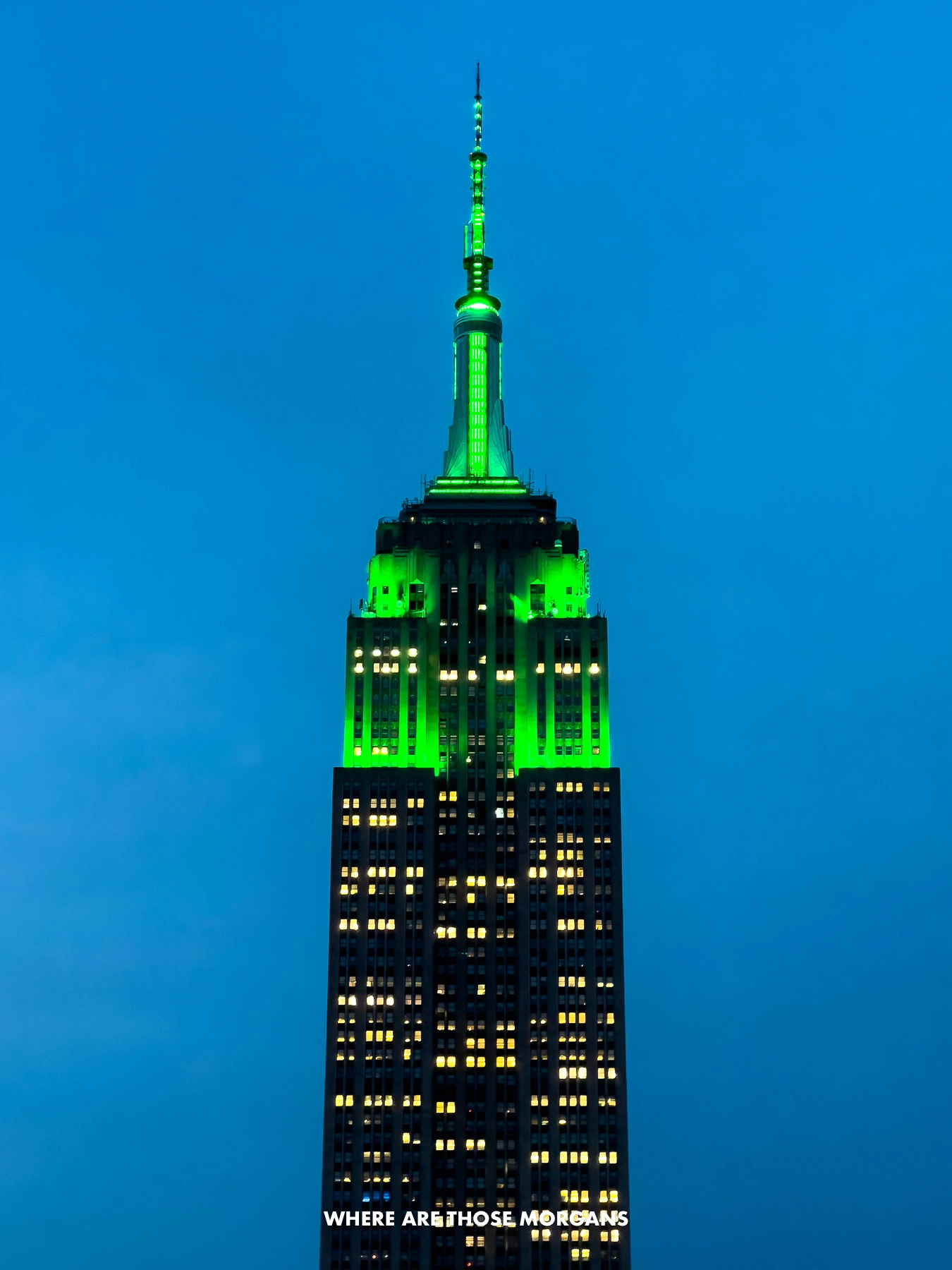 Close up of the Empire State Building lit up green at night