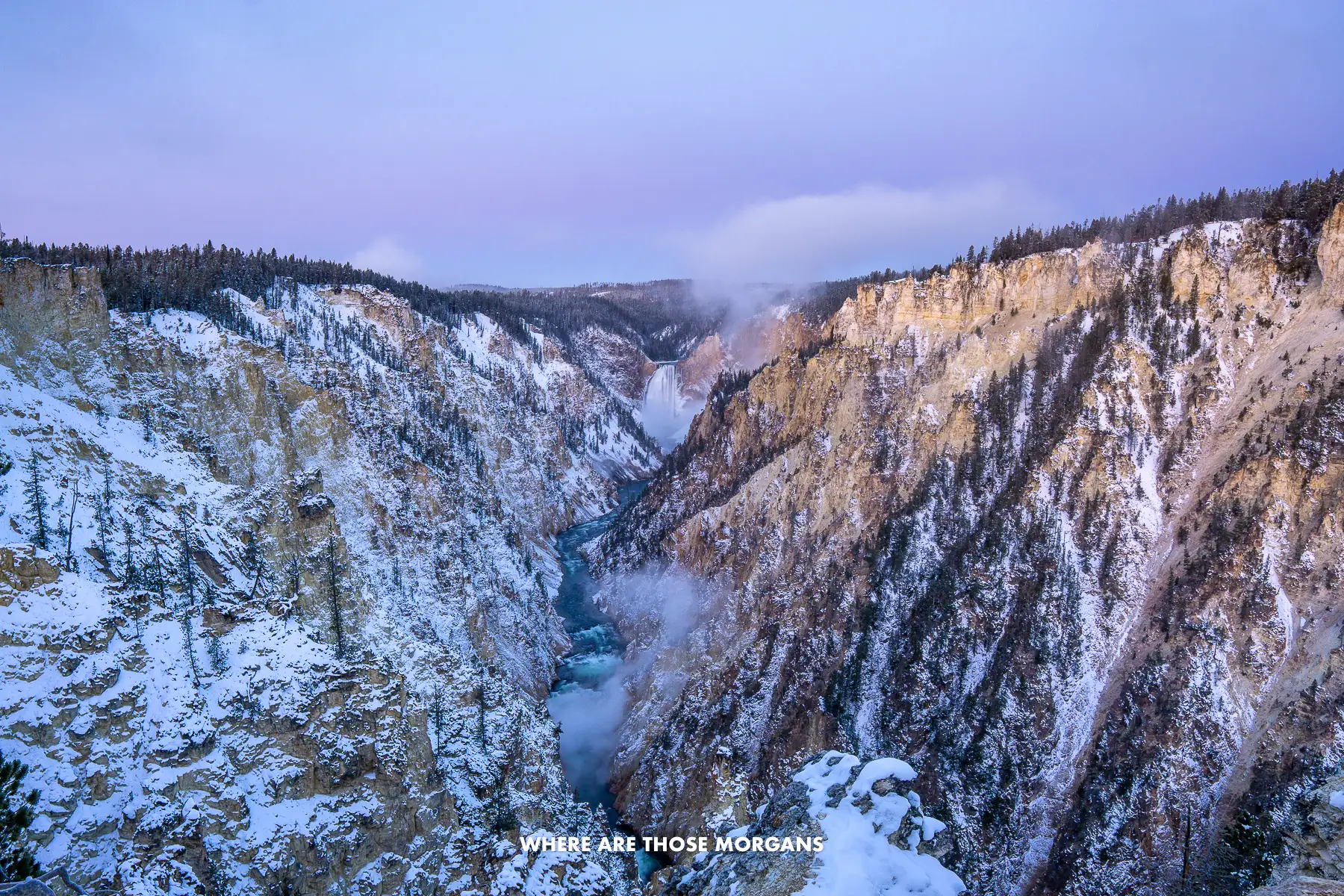 Pink and purple clouds in the sky above Grand Canyon of the Yellowstone at sunrise with a massive waterfall at the end of a V-shaped canyon