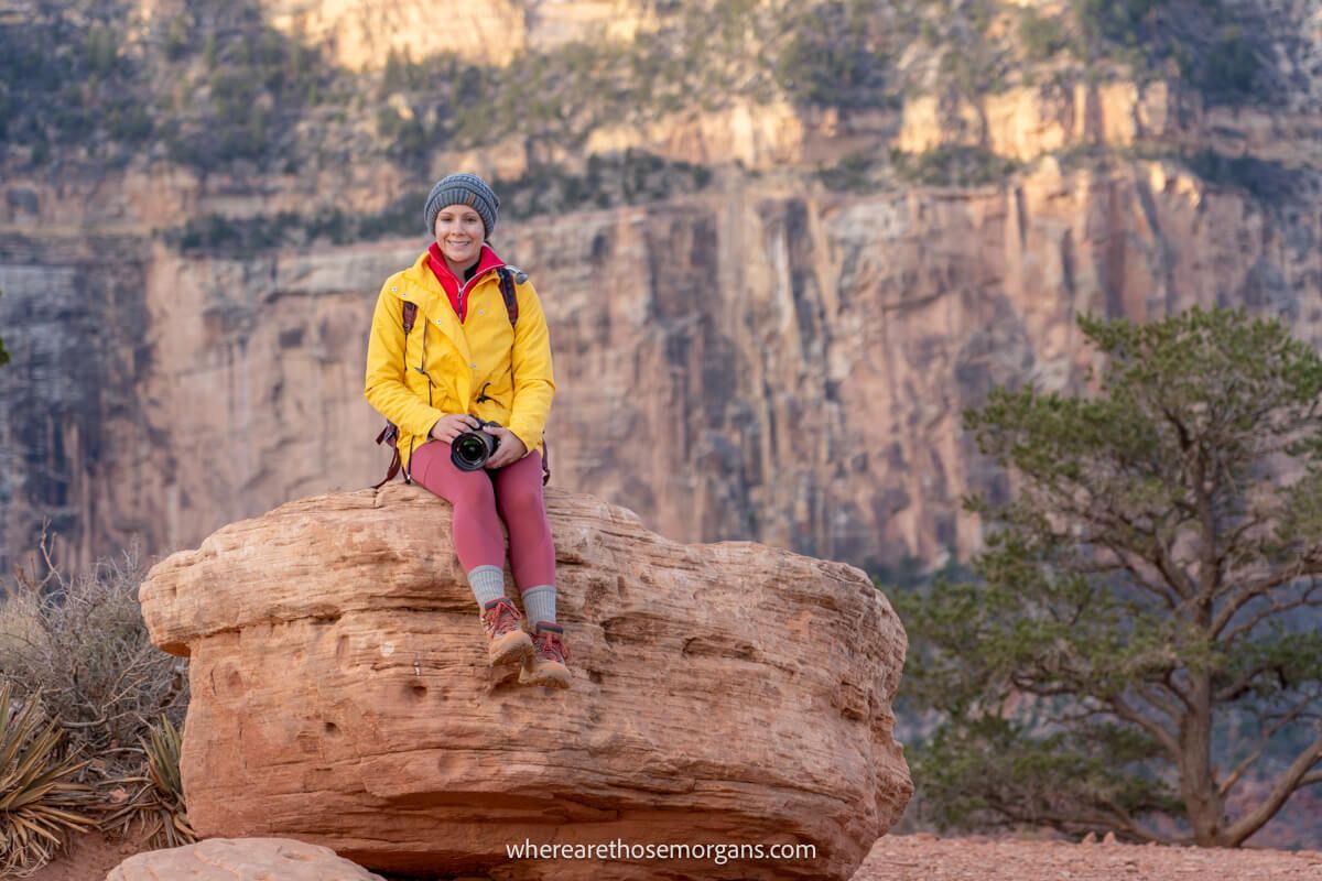 Photo of Kristen Morgan from Where Are Those Morgans in winter gear sat on a large rock with a camera on a hike in the Grand Canyon