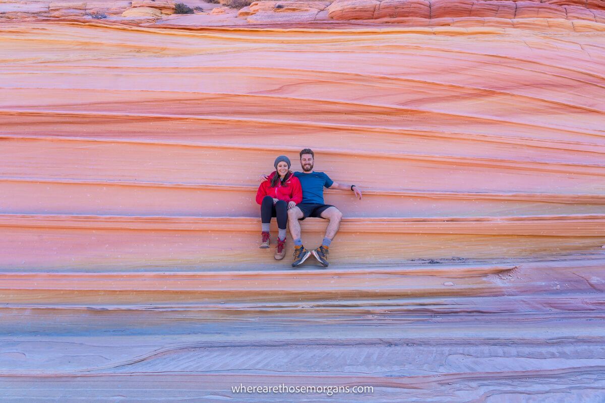 Photo of a couple sitting together on a vibrantly colored rock formation with sediment layers