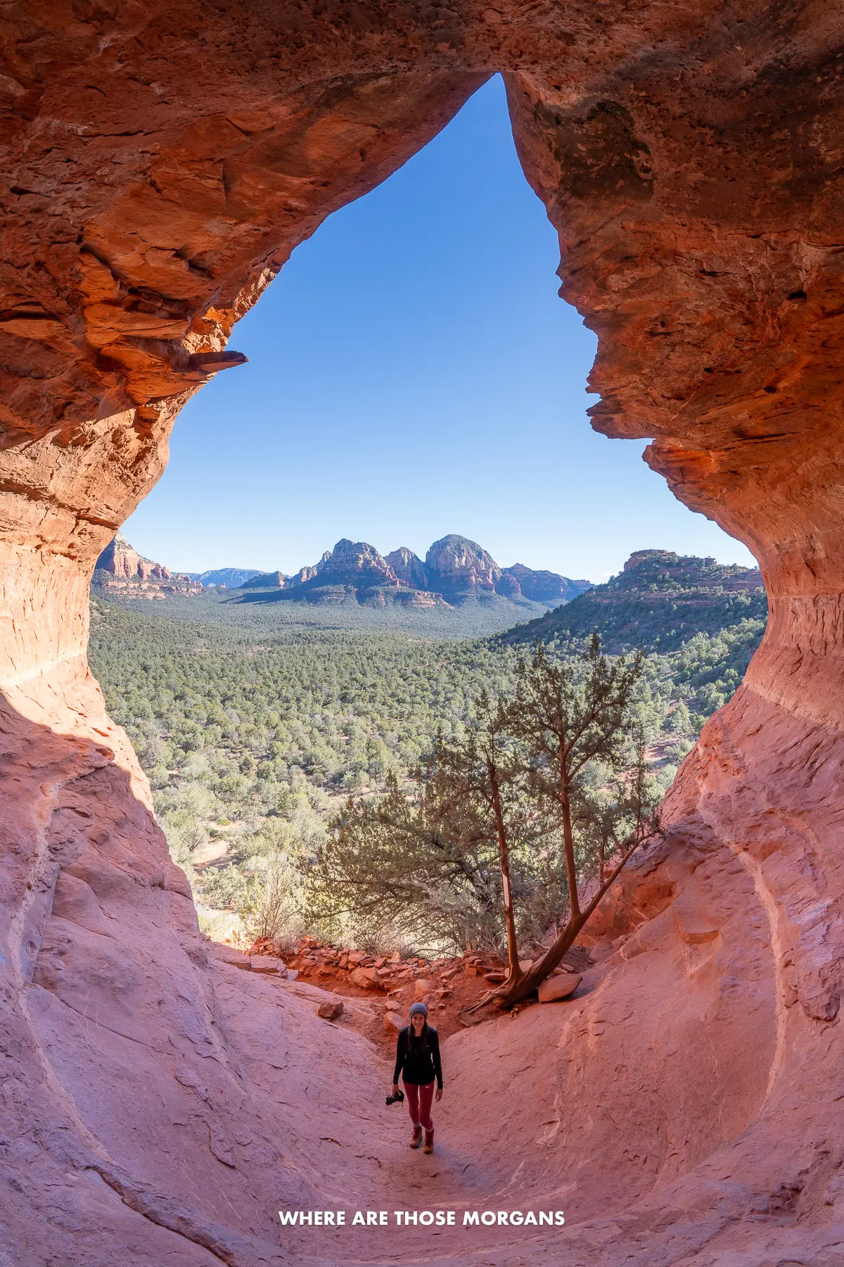 Kristen from Where Are Those Morgans standing alone at the bottom of Sedona's Birthing Cave with the flame shaped cave entrance and far reaching views behind