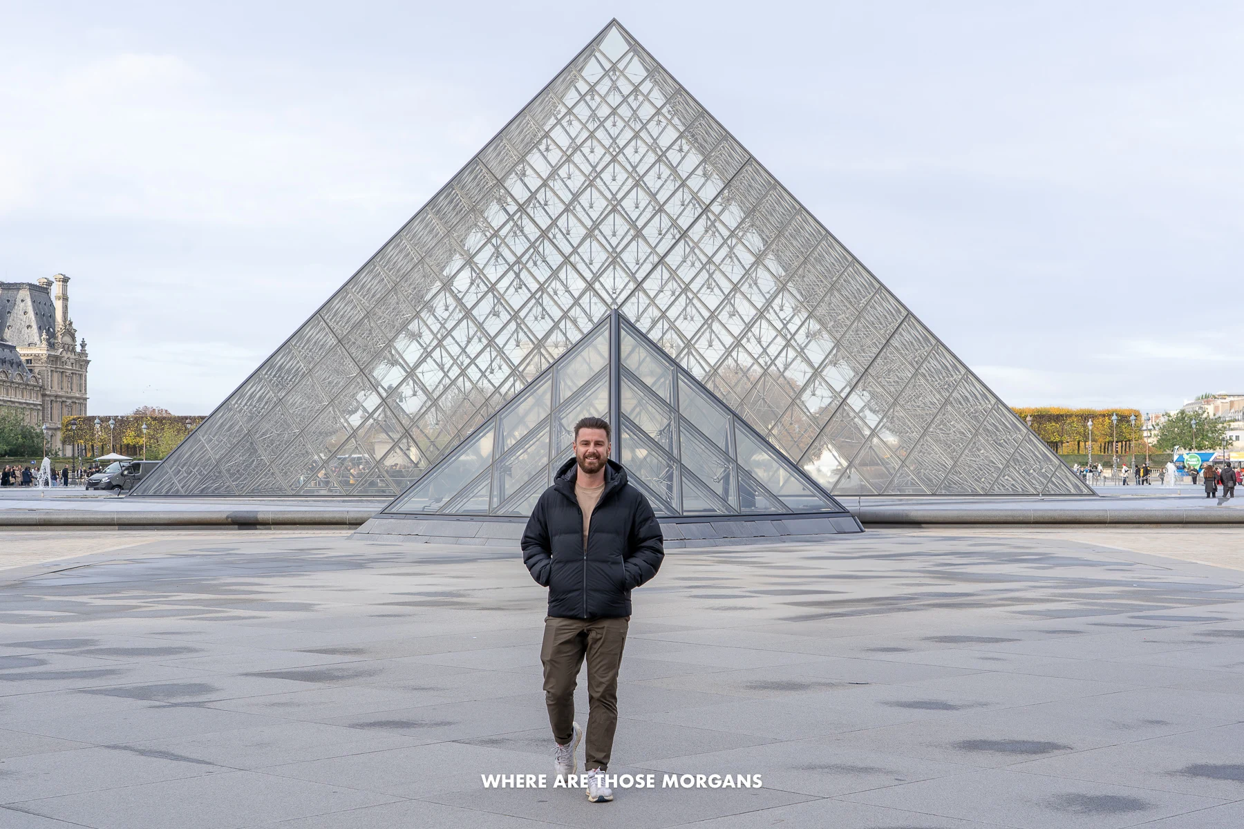 Photo of Mark Morgan walking outside the glass pyramid of the Louvre