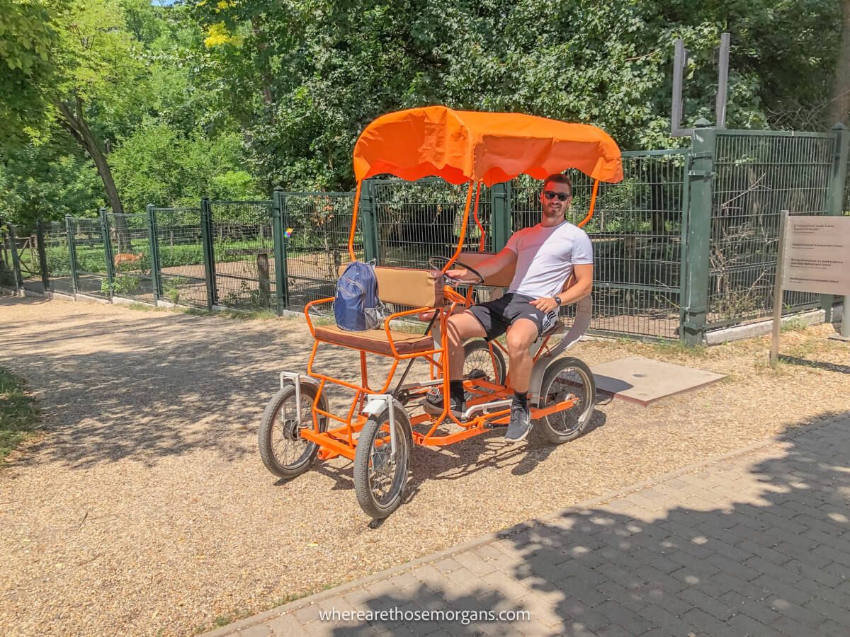 Tourist riding a quad bicycle with orange canopy in a park