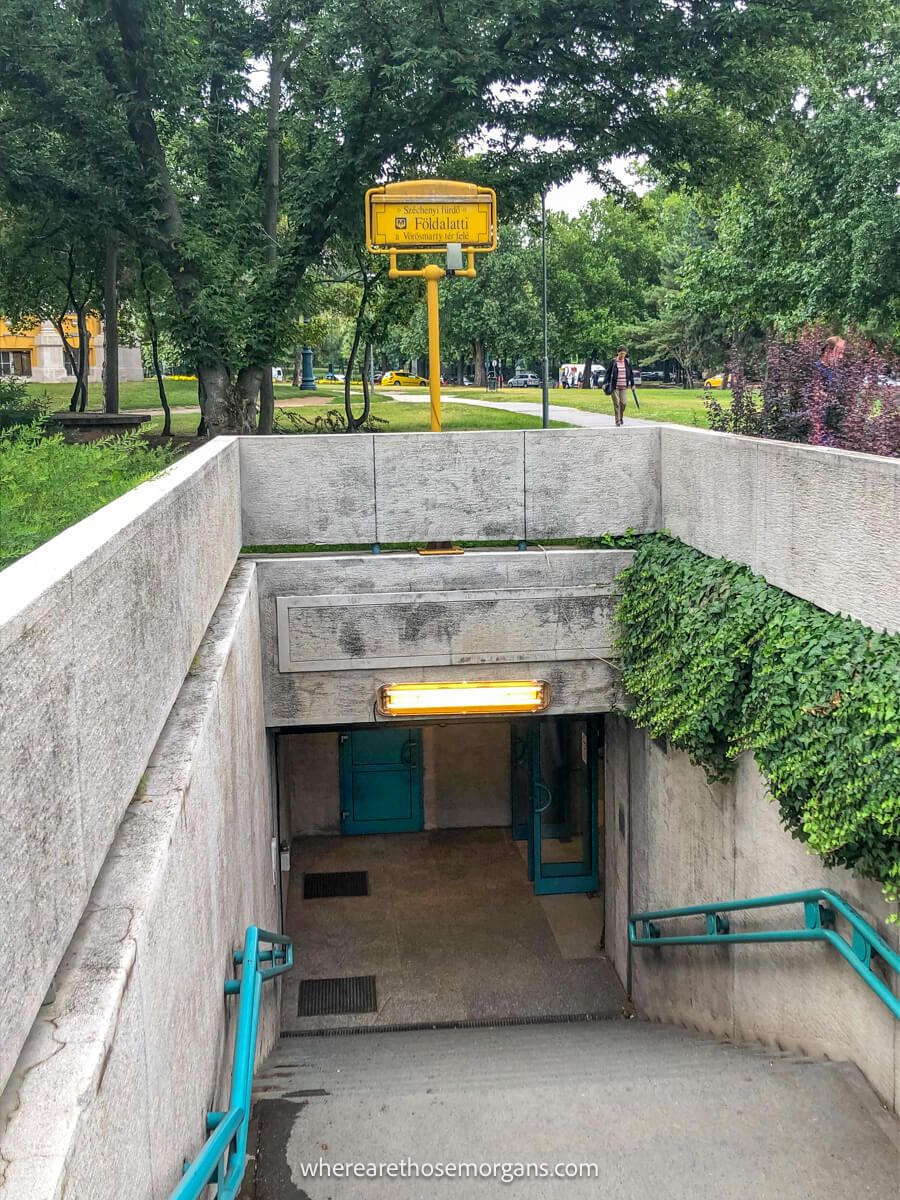 Photo of a staircase leading down into a metro station in Budapest with trees behind