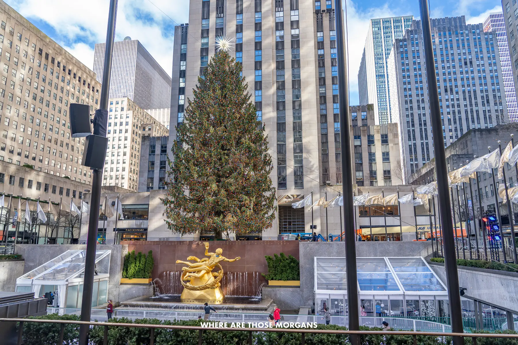 The Rockefeller Christmas Tree behind the famous ice rink with a few people skating