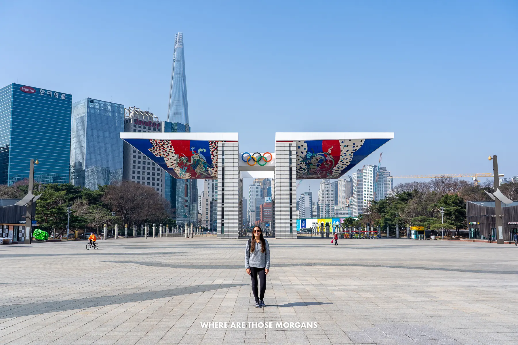 Kristen from Where Are Those Morgans standing in a massive plaza in front of Seoul Olympic Park Peace Gate on a sunny day with skyscrapers behind