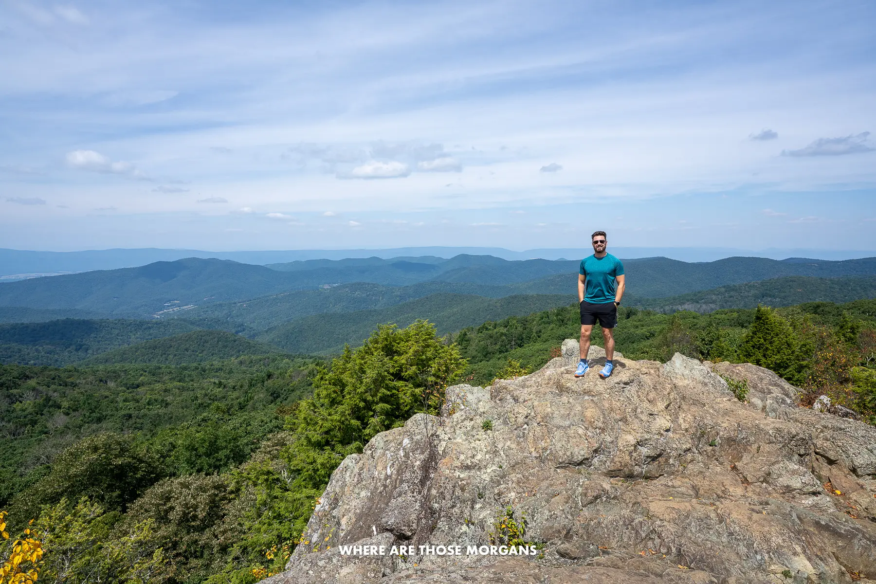 Mark from Where Are Those Morgans hiking on rocks with wide open views of rolling hills behind