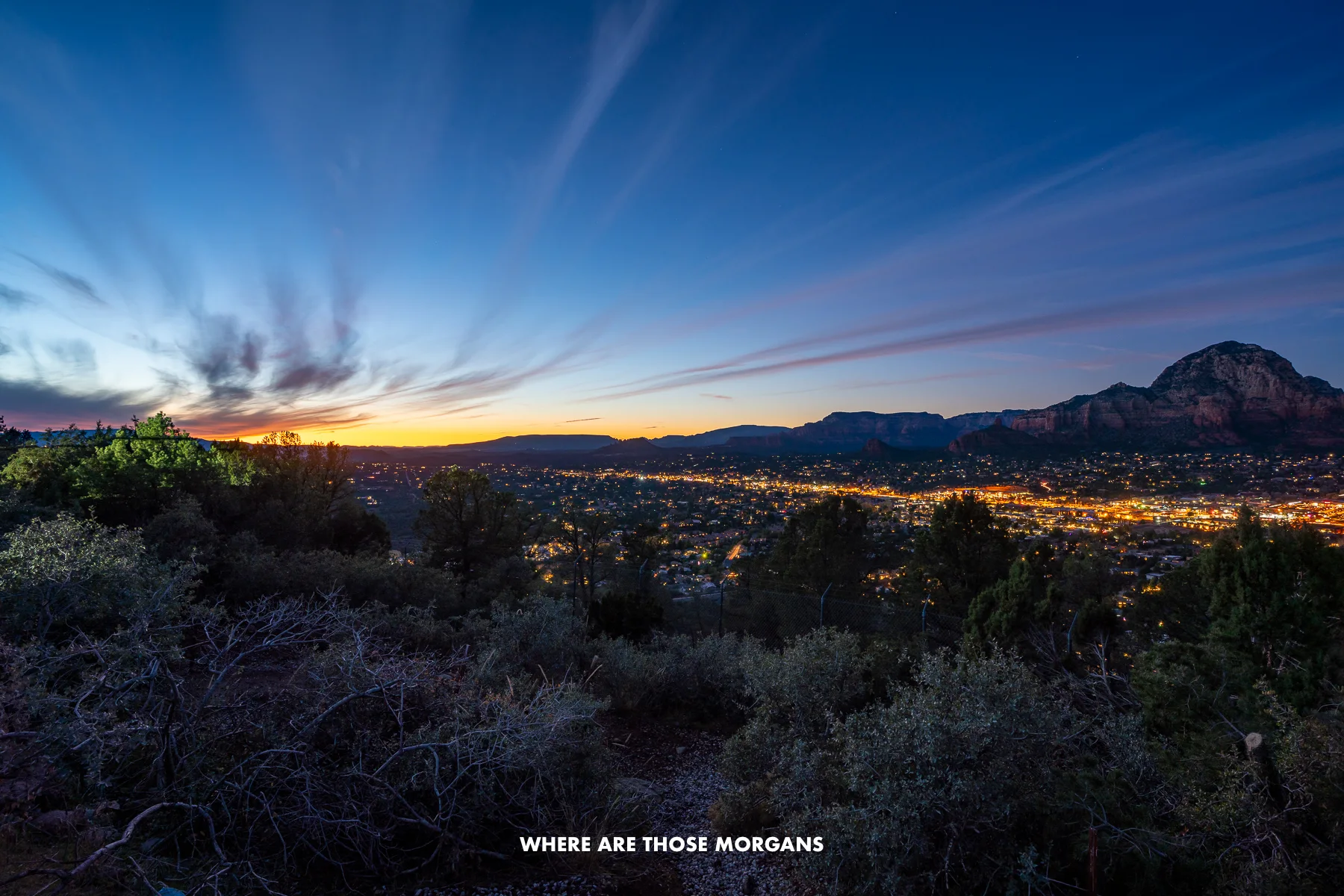 View of Sedona lit up at dusk with sunset colors in the sky from Airport Mesa