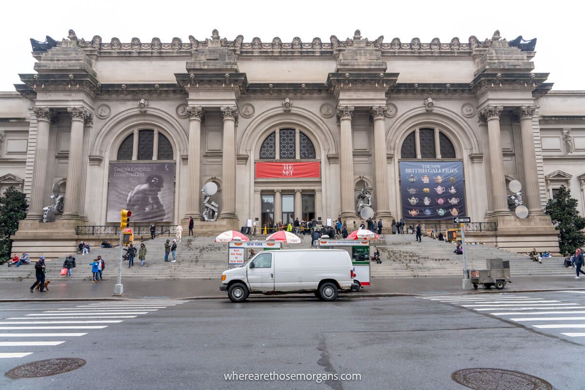 Exterior photo of the Met museum in New York City with a van parked and tourists walking around