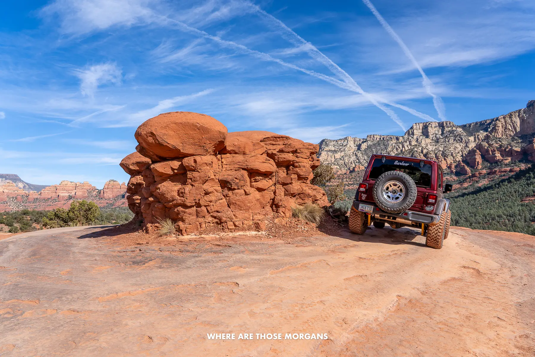 Jeep driving in a circle around a rounded rock formation in Arizona