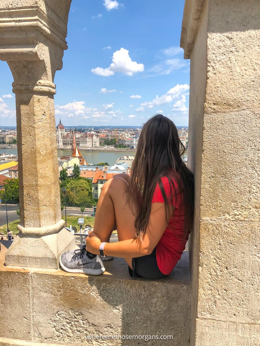Tourist sat in a fortress window overlooking Budapest and the Danube on a sunny day