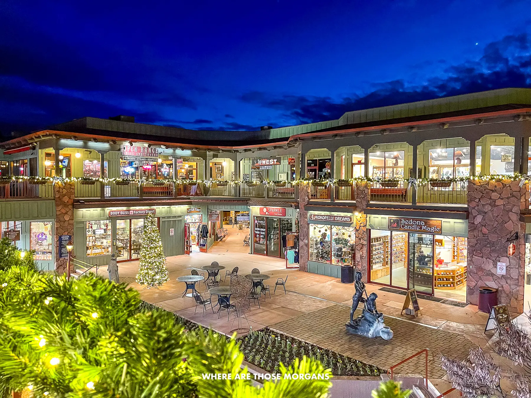 Two story strip mall in Uptown Sedona lit up at night with shop lights glowing